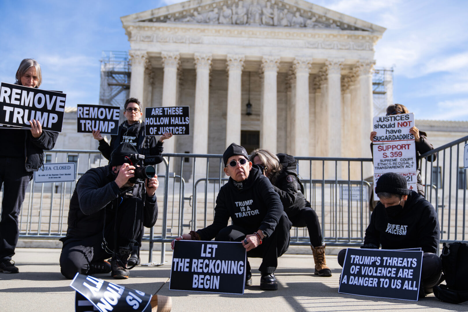 Demonstrators hold signs outside the Supreme Court as the justices heard arguments Thursday on whether Colorado could keep former President Donald Trump off the 2024 presidential primary ballot.