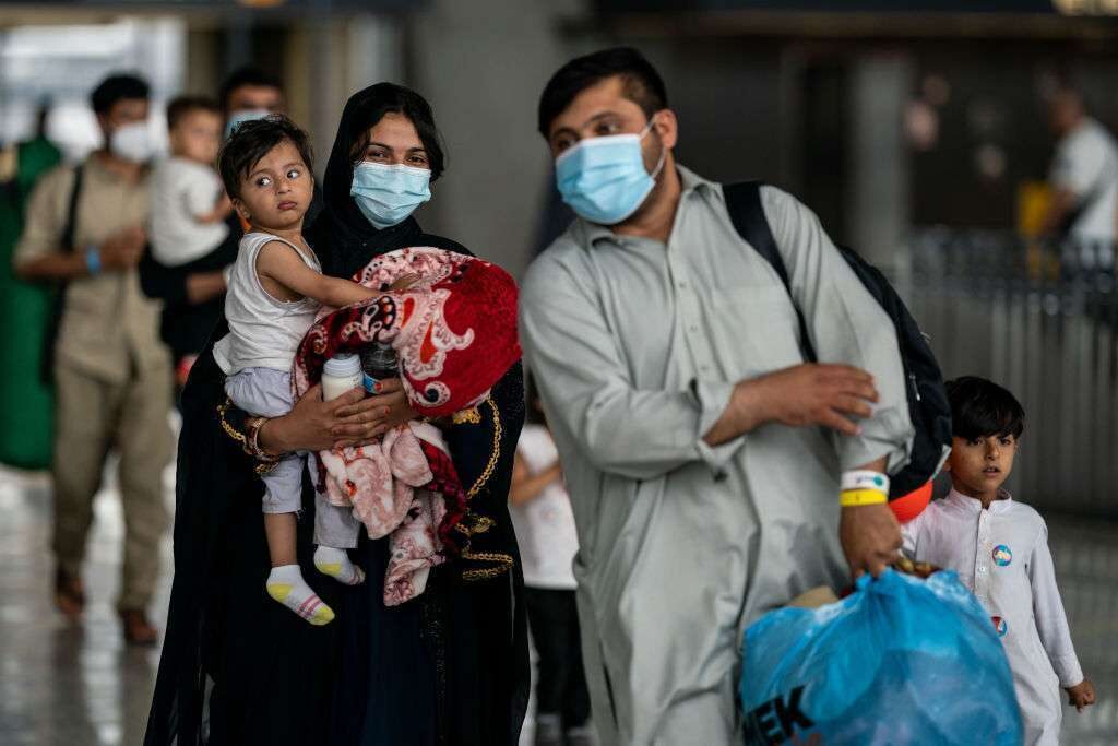 Evacuees who fled Afghanistan walk through a terminal at Dulles International Airport in August 2021 to board buses that will take them to a processing center.  Refugees arrived in the United States after the U.S. withdrew troops from Afghanistan.