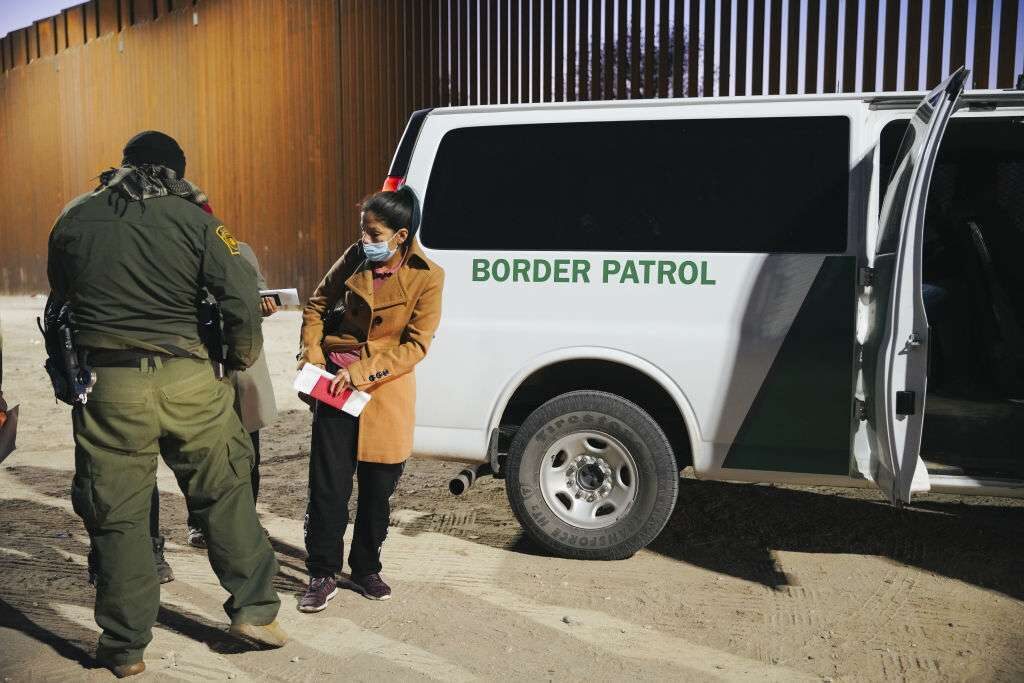 An asylum seeker waits to board a Customs and Border Protection bus to an immigration facility, after turning herself in at the U.S-Mexico border in Yuma, Arizona, in February. 