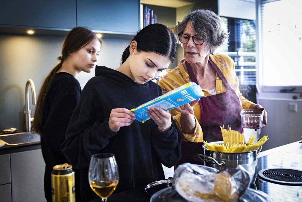 Ukrainian sisters Katja, left, and Varja cook dinner Wednesday with a member of a Dutch foster family in The Hague, Netherlands. The sisters fled Kyiv with their mother at the beginning of the war, while their father remained behind.