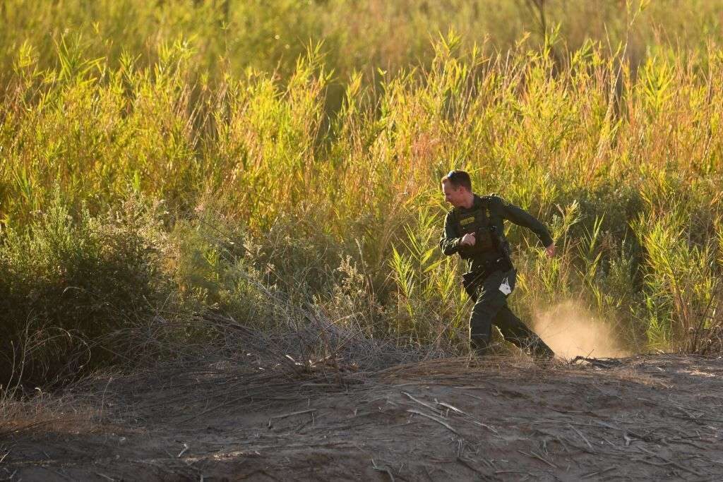 A Border Patrol agent searches for someone crossing through the Colorado River into the U.S. ahead of the border wall between the US and Mexico in Yuma, Ariz., in June. 