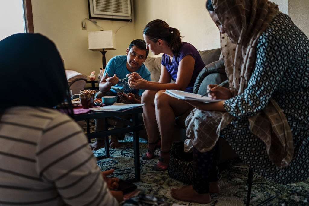 Shir Agha Safi, 30, helps Sadye Katherine Scott-Hainchek, 36, center, a volunteer helping Afghan refugees fill out asylum paperwork in August in Des Moines, Iowa. Safi, a refugee who was an Afghan military commander who used to lead men into battle against insurgent and terrorists, started a nonprofit organization called Afghan Partners in Iowa that aims to train Afghan refugees who speak English to help fellow Afghan refugees with their needs and challenges.