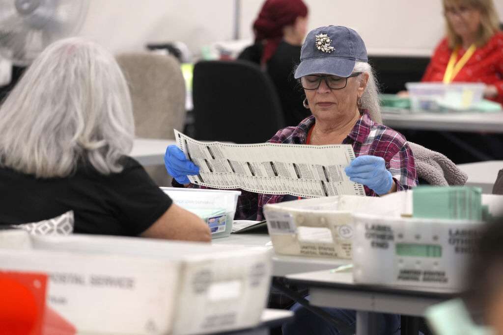 Election workers open mail in ballots at the Maricopa County Tabulation and Election Center on Nov. 11 in Phoenix. 