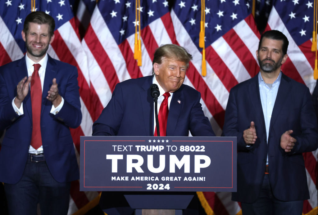 Former President Donald Trump speaks at his caucus night event, with sons Eric Trump and Donald Trump Jr. looking on, at the Iowa Events Center on Monday in Des Moines, Iowa. 