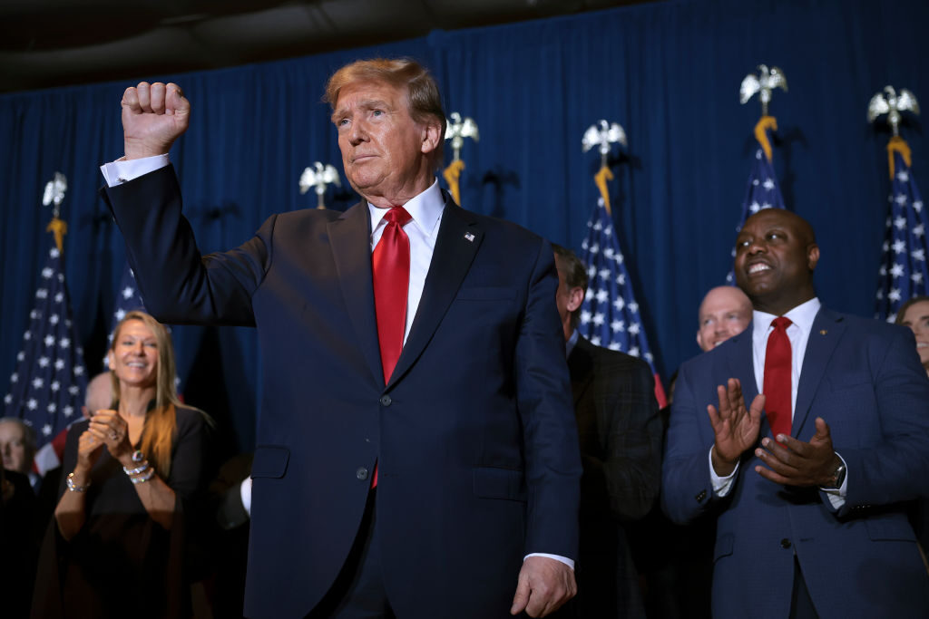 Republican presidential candidate and former President Donald Trump gestures to supporters and Sen. Tim Scott applauds on Saturday in Columbia, S.C. after Trump won the South Carolina primary.