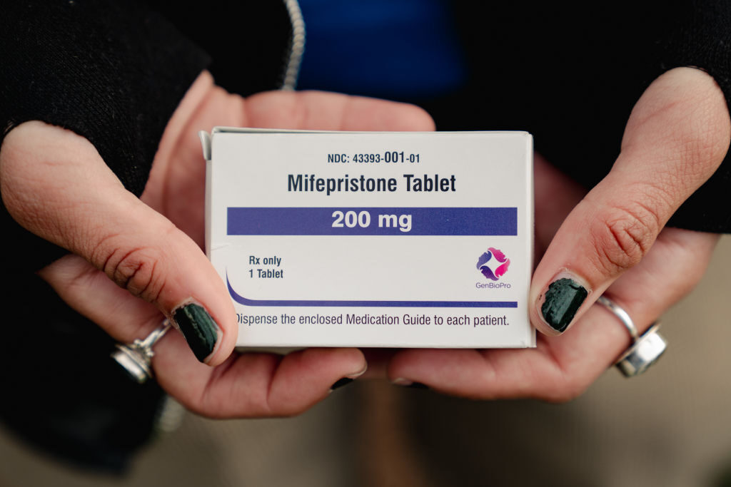 An abortion rights advocate shows a box of mifepristone outside the Supreme Court building in March. 