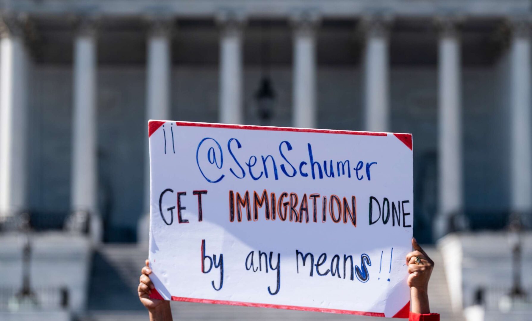 Immigration advocates hold signs outside the Capitol on Sept. 27, 2021. With legislation stalled, Democrats are considering executive action to help more immigrants.