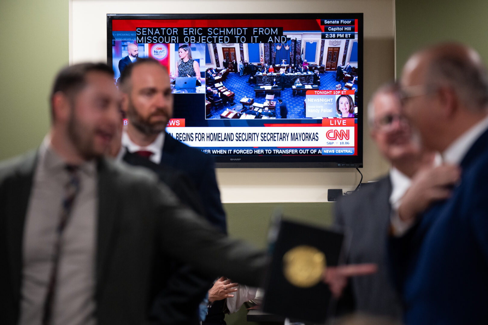 Visitors in the Hart Senate Office Building go about their business as floor action Wednesday on the impeachment articles against Homeland Security Secretary Alejandro Mayorkas airs on television in the background. 