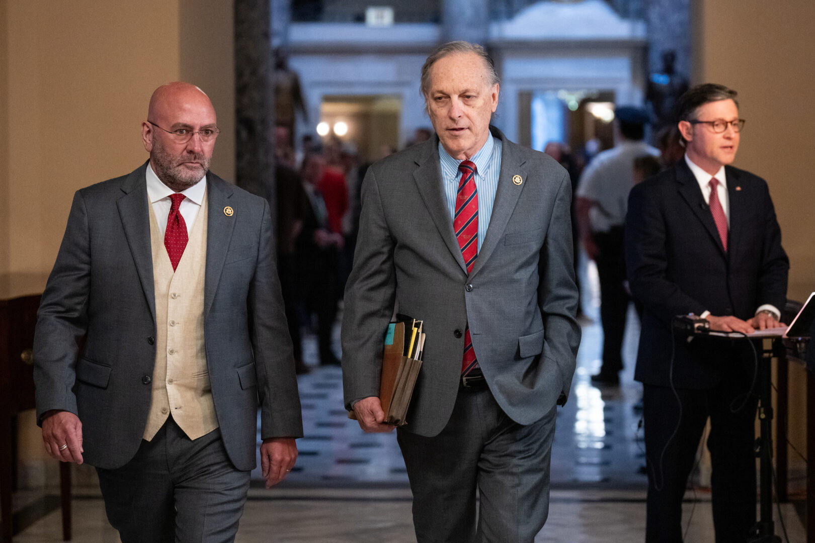 Secretary of Homeland Security Alejandro Mayorkas impeachment managers Rep. Clay Higgins, R-La., left, and Rep. Andy Biggs, R-Ariz., return to the House side Wednesday after the end of the Mayorkas impeachment in the Senate, as Speaker Mike Johnson, R-La., conducts a TV news interview. 