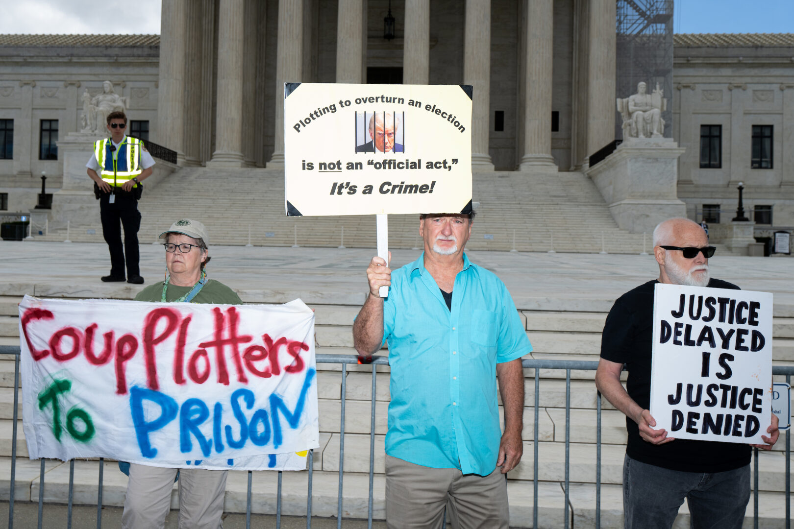 Protesters hold signs in front of the Supreme Court in Washington while waiting Monday for the court to announce its decision on presidential immunity. 