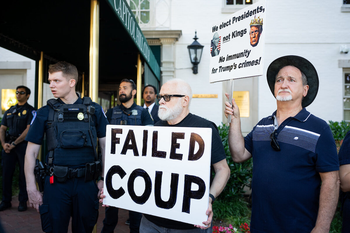 Protesters hold signs outside of House Republicans’ meeting with former President Donald Trump at the Capitol Hill Club on Thursday. (Bill Clark/CQ Roll Call)